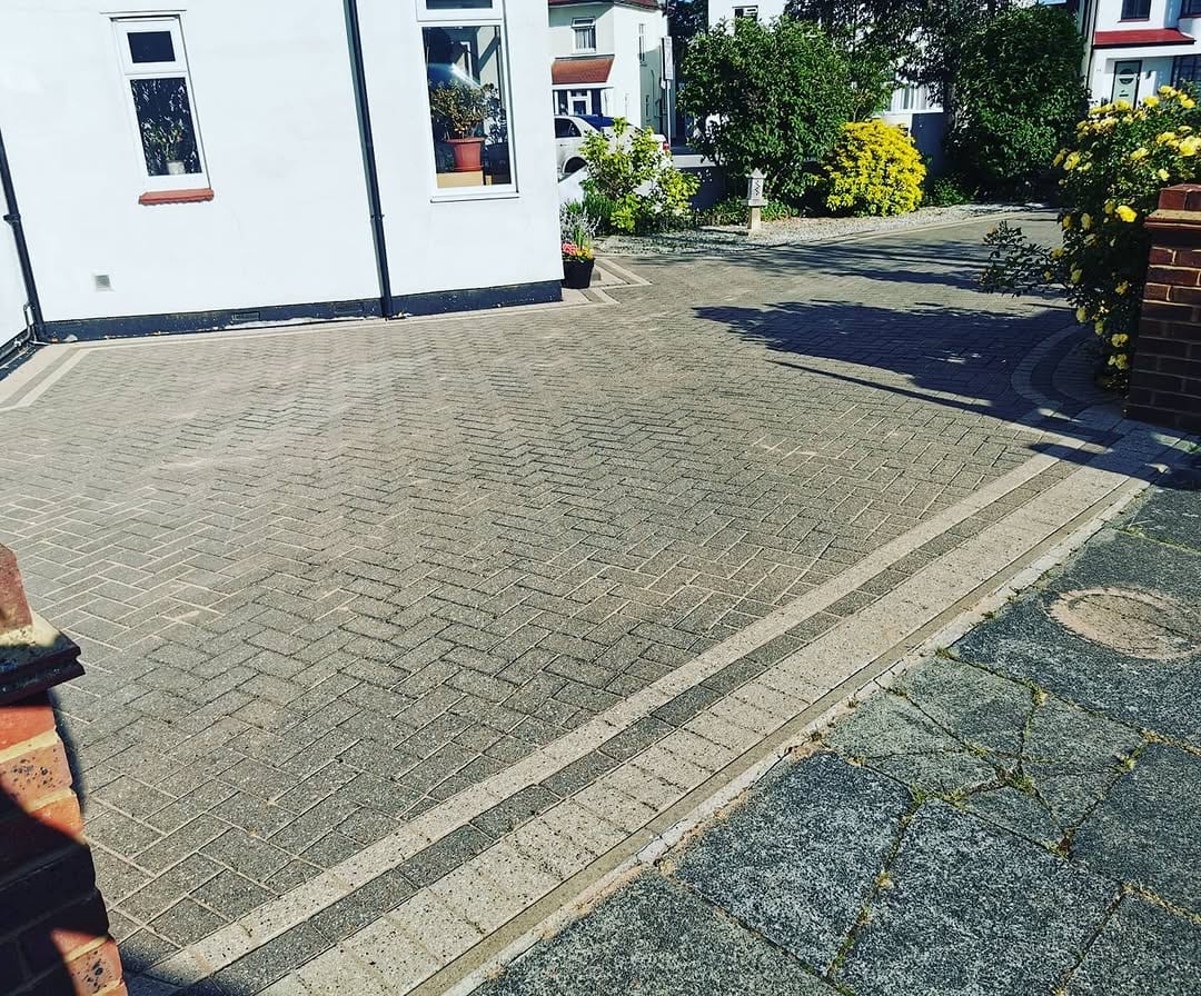 A cleaned herringbone block-paved driveway beside a white house