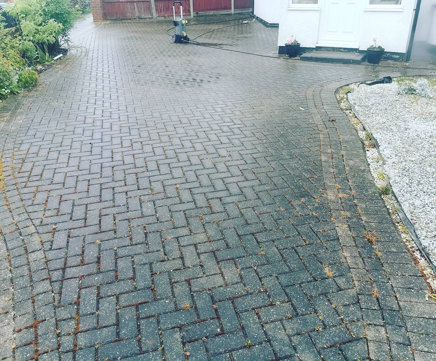 Driveway mid pressure-wash, weeds still visible in the joints