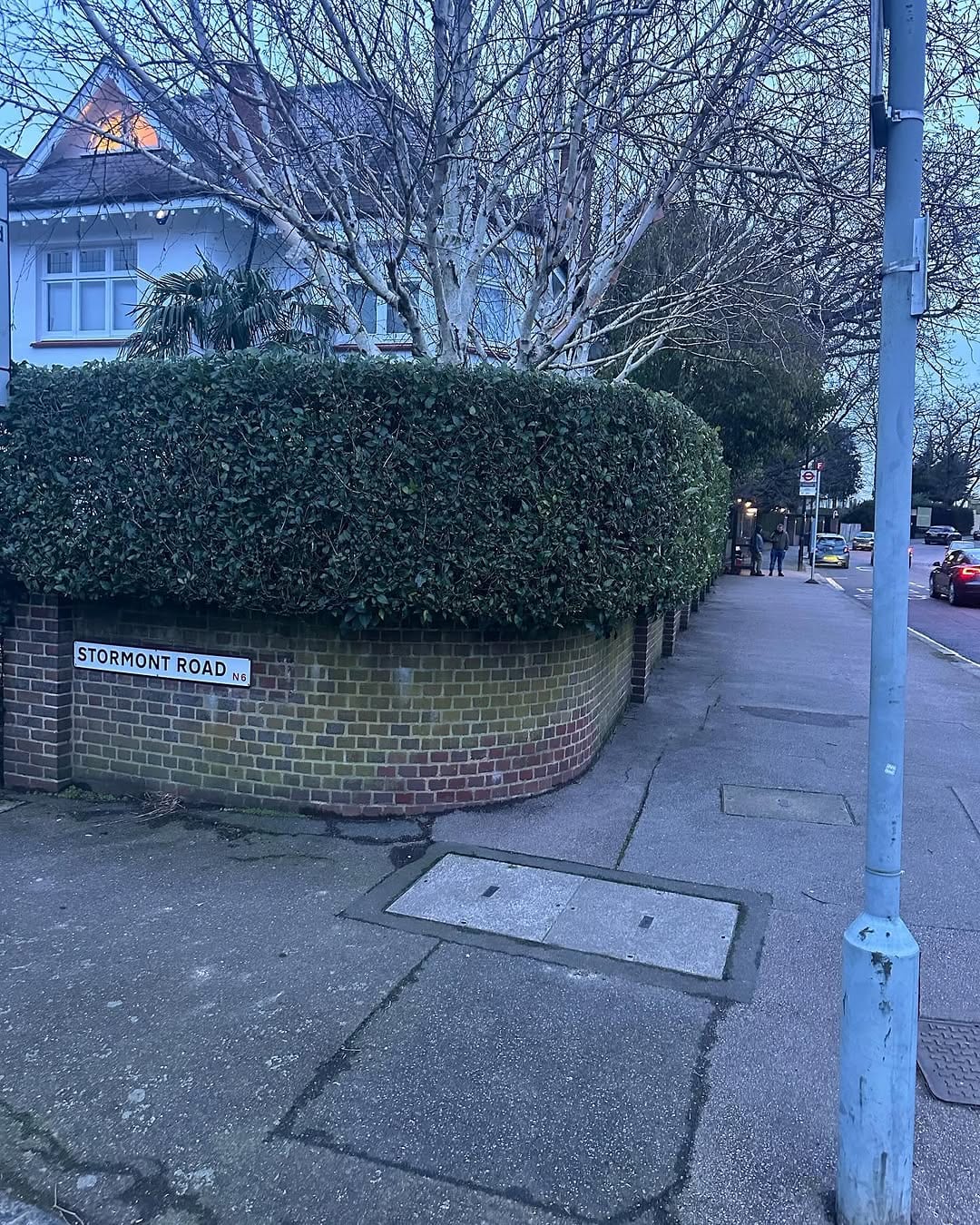 A neatly trimmed hedge atop a brick wall on Stormont Road, North London, with the street sign visible